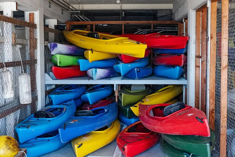 Colorful kayaks stacked in an indoor storage area, showcasing vivid designs