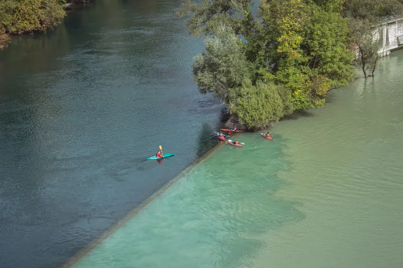 Stunning aerial shot of kayakers at the confluence of two rivers, showcasing vibrant water color contrast