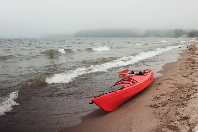 Red kayak on a misty beachside in Jönköping, Sweden. Perfect for outdoor recreation