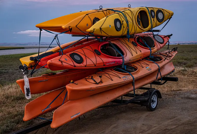 Colorful kayaks stacked on a trailer ready for adventure in a scenic outdoor setting