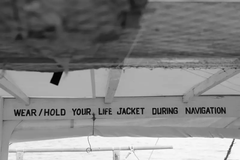 Black and white sign promoting life jacket safety on a ship