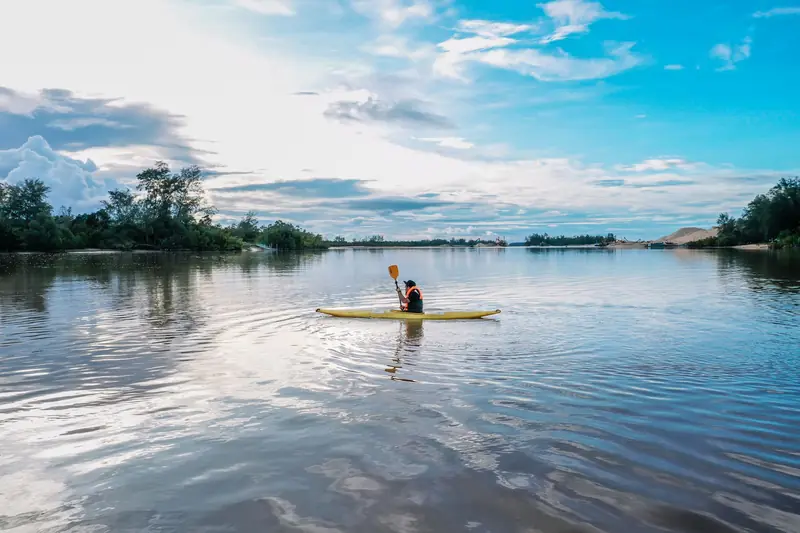 A scenic kayak ride on a tranquil river in Terengganu, Malaysia, surrounded by lush greenery