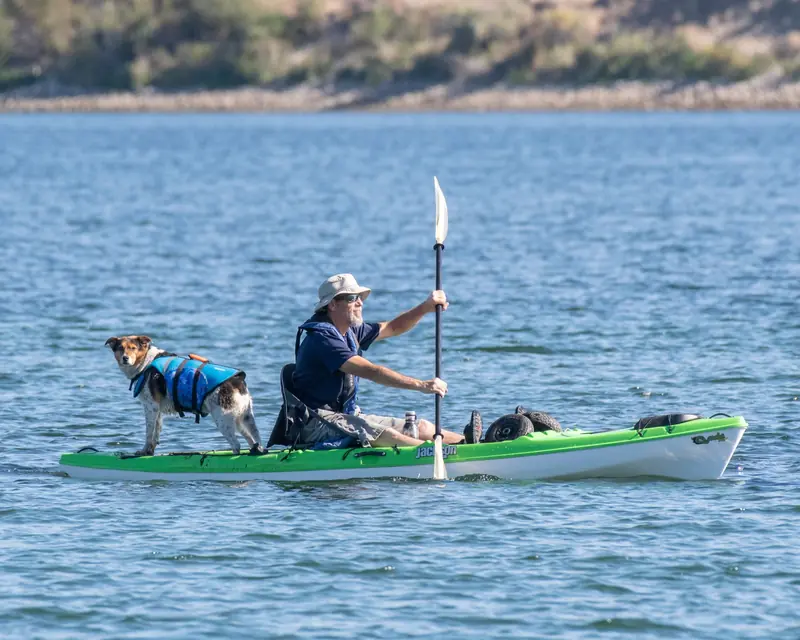 A man paddles a kayak with his dog on the Wenatchee River, enjoying a sunny day outdoors