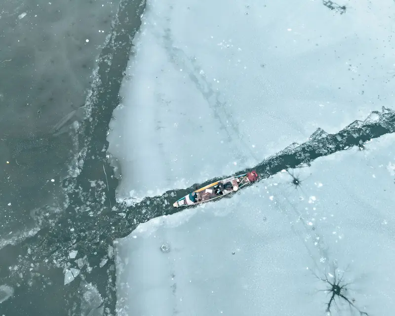 Kayak moving through icy landscape in winter, captured from above