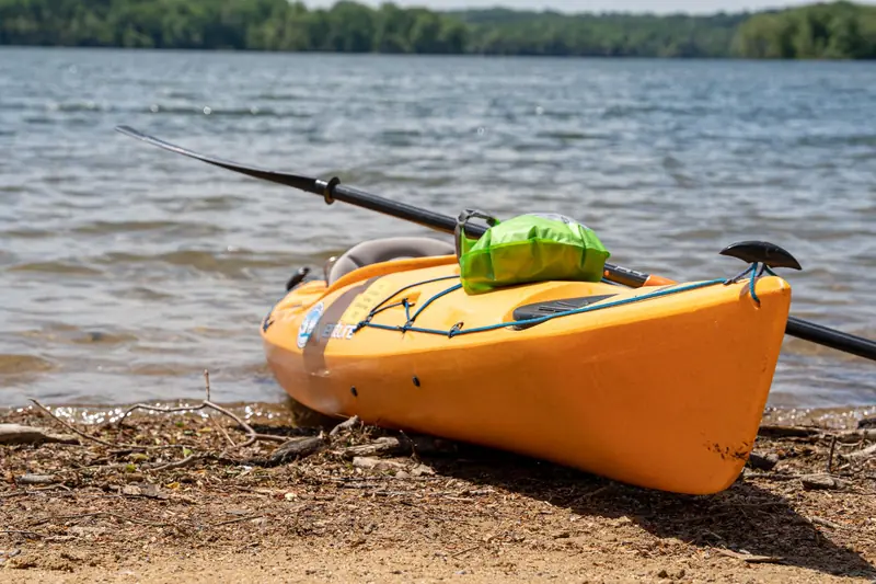Vibrant yellow kayak resting on a tranquil lakeshore, ideal for summer adventures