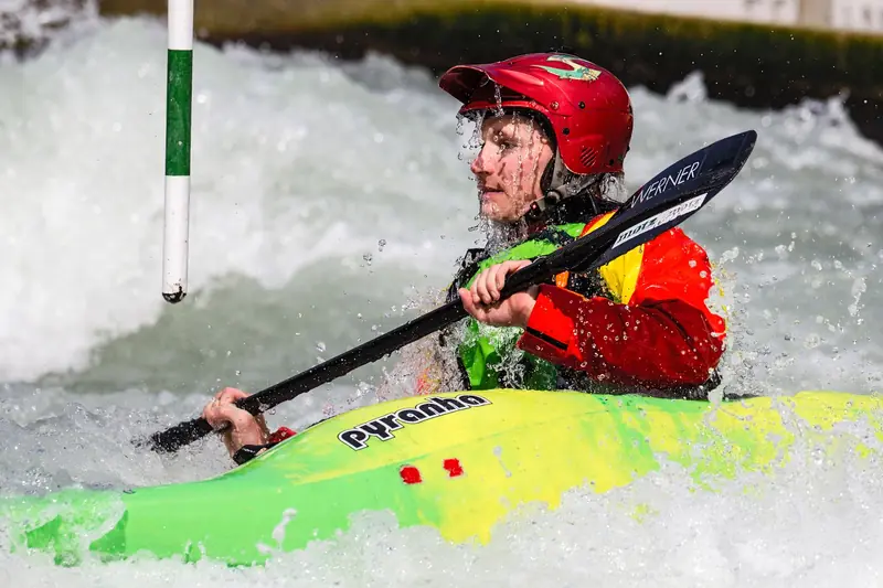 Dynamic action shot of a kayaker navigating rapids in a vibrant kayak, wearing safety gear